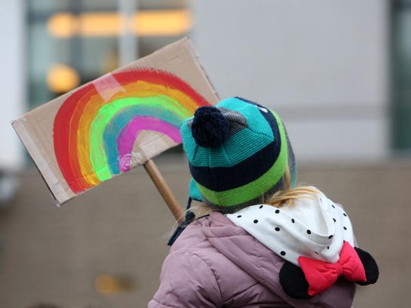 Für eine bunte Regenbogengesellschaft: Eine junge Demonstrantin hält am 21. Januar 2024 in Berlin ein Pappschild mit einem abgebildeten Regenbogen hoch. 