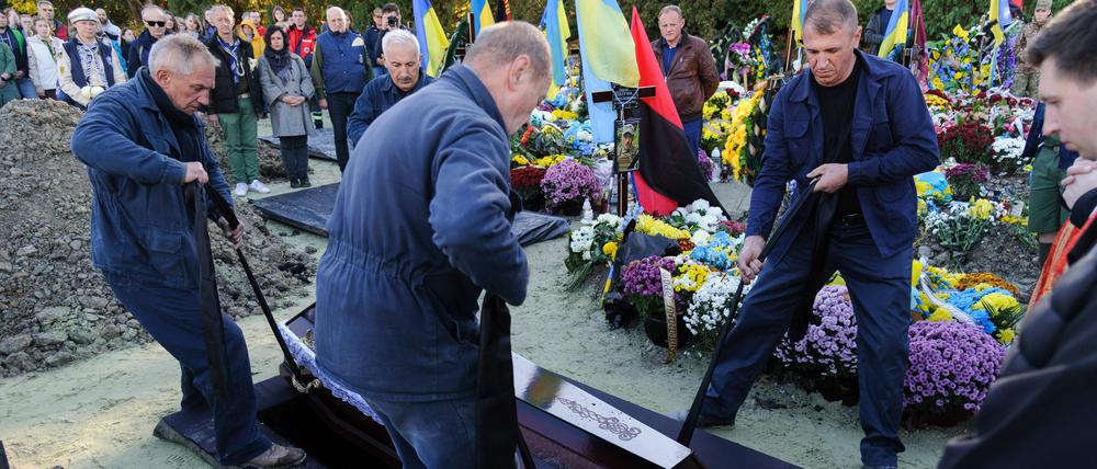 Lviv, Ukraine: Bestatter senken den Sarg des ukrainischen Soldaten Taras Havrylyshyn, eines ehemaligen Mitglieds der nationalen Pfadfinderorganisation Plast, ins Grab. 