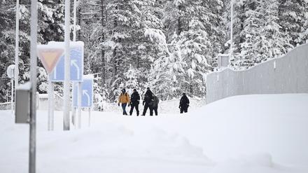 Finnische Grenzschützer eskortieren zwei Migranten.