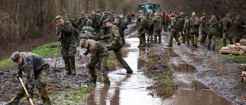 Soldatinnen und Soldaten der Bundeswehr sichern einen Deich an der Helme mit Sandsäcken. 
