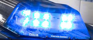 Ein Blaulicht leuchtet auf dem Dach eines Polizeiwagens. Im Hintergrund steht ein weiterer Streifenwagen. 