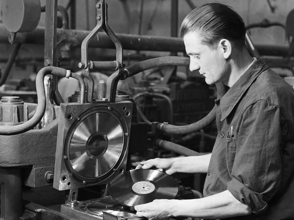 Ein Arbeiter 1948 mit einer LP an der Schallplattenpresse.