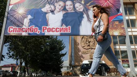 Eine Frau geht an einem Plakat vorbei, auf dem das 15-jährige Jubiläum der Anerkennung der Unabhängigkeit Südossetiens durch Russland gefeiert wird (Archivbild vom 21. August 2023).