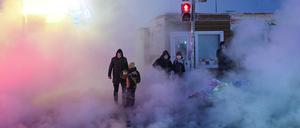 Menschen auf einer Straße in Novosibirsk (Russland), wo ein großer Heizkraftwerkausfall für Dampf auf der Straße sorgt.