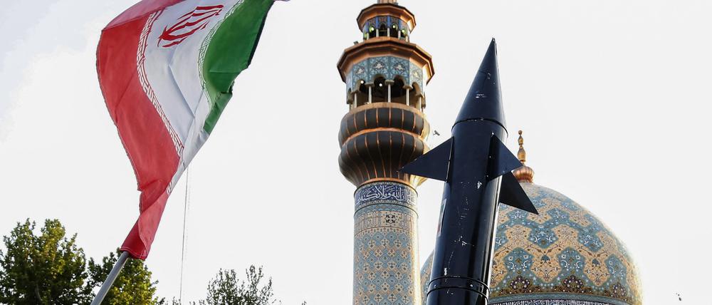Iraner heben eine Flagge und die Attrappe einer Rakete während einer Feier nach dem iranischen Raketen- und Drohnenangriff auf Israel. 