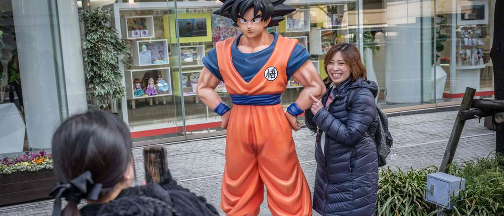 Ein „Dragon-Ball“-Fan in Tokio neben einer Statue der Hauptfigur Son Goku.
