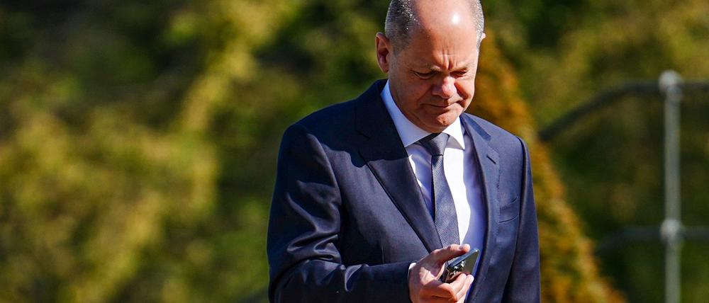 Bundeskanzler Olaf Scholz (SPD) schaut im Garten vor dem Schloss Meseberg, dem Gästehaus der Bundesregierung, kurz vor Beginn der Kabinettssitzung auf sein Smartphone. 