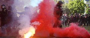 Bei Protesten gegen das Urteil im Prozess gegen Lina E. in Leipzig stehen Polizisten in roten Qualm, nachdem linke Demonstranten Pyrotechnik gezündet und geworfen hatten.