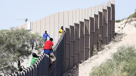 Migranten klettern über einen Zaun auf der sizilianischen Insel Lampedusa.
