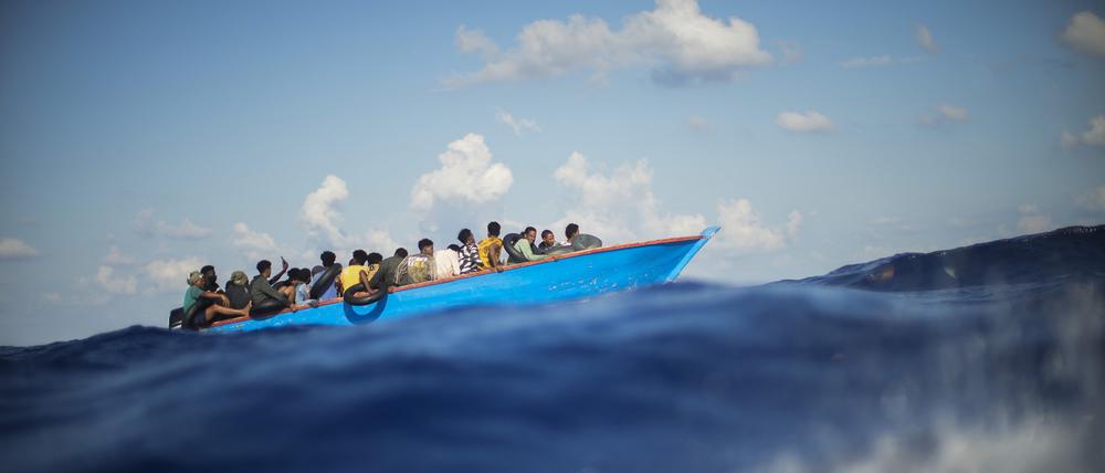 Migranten sitzen in einem Holzboot südlich der italienischen Insel Lampedusa auf dem Mittelmeer (Archivbild).