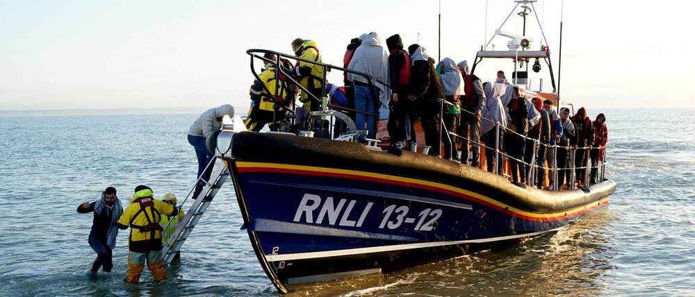 21.09.2022, Großbritannien, Dungeness: Eine Gruppe von Menschen, bei denen es sich vermutlich um Migranten handelt, wird von der Royal National Lifeboat Institution (RNLI) nach einem Zwischenfall mit einem kleinen Boot im Ärmelkanal nach Dungeness in der Grafschaft Kent gebracht. Foto: Gareth Fuller/PA Wire/dpa +++ dpa-Bildfunk +++