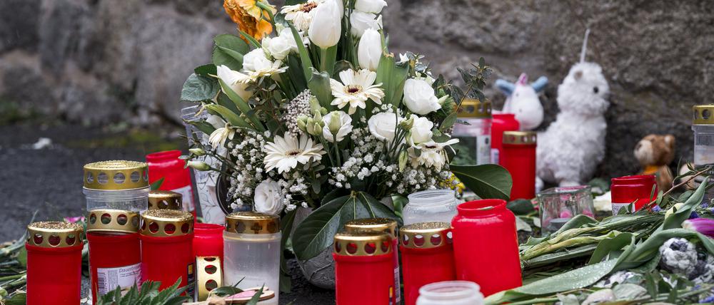 An der Straßenecke zur Zufahrtsstraße zum Kinder- und Jugendhilfezentrum, in dem eine Zehnjährige tot aufgefunden wurde, liegen Blumen, Kuscheltiere und Grablichter auf dem Gehweg.