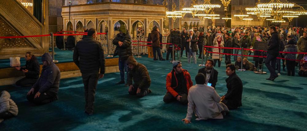 Muslime beten im linken Bereich der Hagia Sophia, während Touristen das Museum auf der rechten Seite besuchen. 