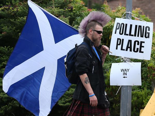 Ein Befürworter der schottischen Unabhängigkeit geht mit einer schottischen Fahne zu einem Wahllokal um über das Unabhängigkeitsreferendum abzustimmen. 
