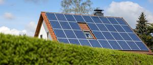 Ein Einfamilienhaus mit Solarpaneelen auf dem Hausdach steht hinter einer grünen Hecke. Mehr als die Hälfte aller Einfamilienhäuser in Europa könnten sich laut einer Studie zurzeit selbst vollständig mit Strom und Wärme versorgen.