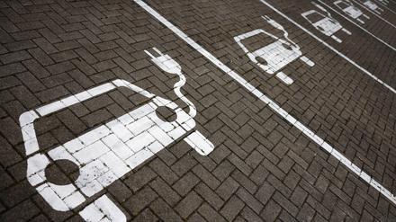 Piktogramme mit Autos, aus denen ein Stromkabel ragt, markieren Parkplätze mit Ladesäulen, an denen Elektro-Autos ihren Akku laden können.