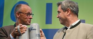 Beim politischen Frühschoppen Gillamoos. Friedrich Merz (l), Bundesvorsitzender der CDU, und Markus Söder (CSU), Ministerpräsident von Bayern, stoßen auf der Bühne mit Bierkrügen an. 