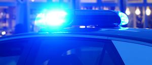 Ein Blaulicht leuchtet auf dem Dach eines Polizeiautos während einer Polizeiabsperrung. 
