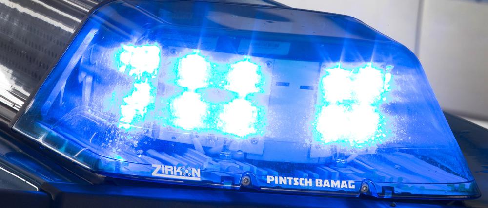 Eine Blaulicht leuchtet auf dem Dach eines Polizeiwagens. 