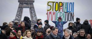 Ein Gegner des französischen Einwanderungsgesetzes hält während einer Demonstration ein Plakat mit der Aufschrift „Stoppt das Einwanderungsgesetz“ auf dem Trocadero-Platz in der Nähe des Eiffelturms.