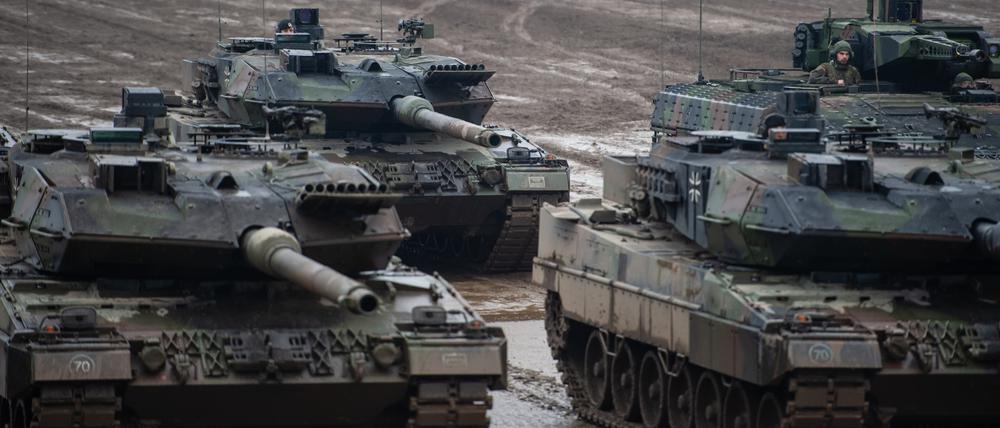Drei Kampfpanzer der Bundeswehr vom Typ Leopard 2A6 und ein Schützenpanzer vom Typ Puma stehen bei einer Übung im Gelände.