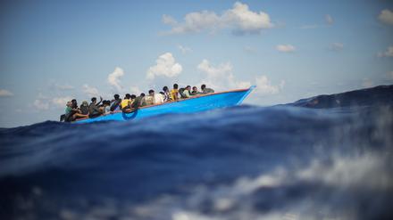 Migranten sitzen in einem Holzboot im Mittelmeer (Symbolbild).
