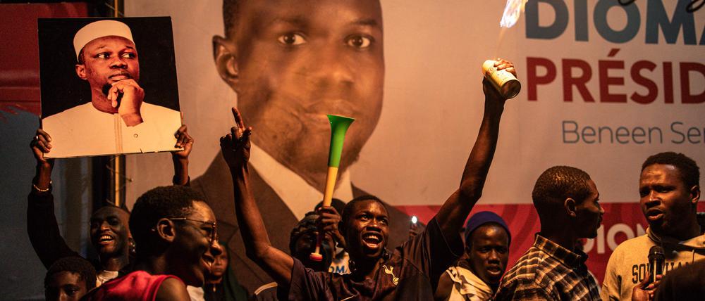 Anhänger des Präsidentschaftskandidaten  Bassirou Diomaye Faye (auf dem großen Plakat) feiern in der Nacht bereits vor dem Hauptquartier der Koalition, die ihn unterstützte. 