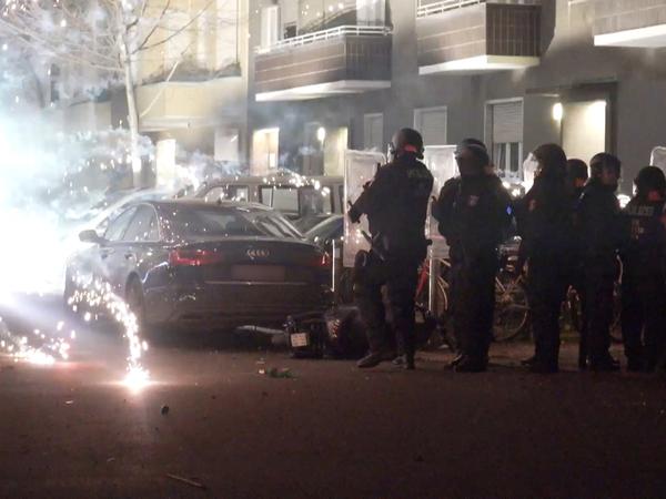 Polizeibeamte stehen hinter explodierendem Feuerwerk. Nach Angriffen auf Einsatzkräfte in der Silvesternacht hat die Diskussion um Konsequenzen begonnen. 