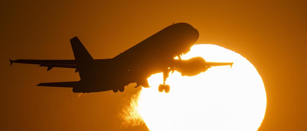 Eine Passagiermaschine hebt vor der untergehenden Sonne vom Flughafen Frankfurt ab. 