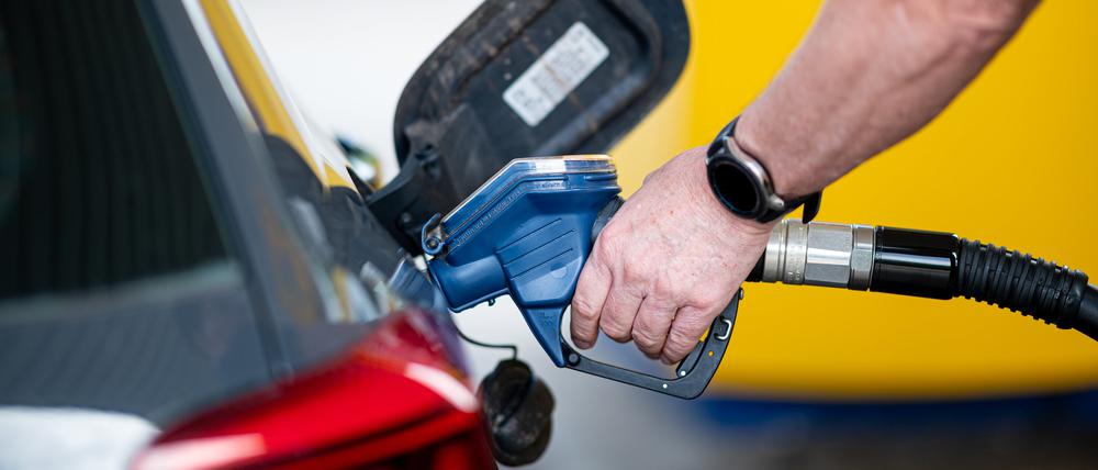 Ein Mann betankt an einer Tankstelle sein Auto. 