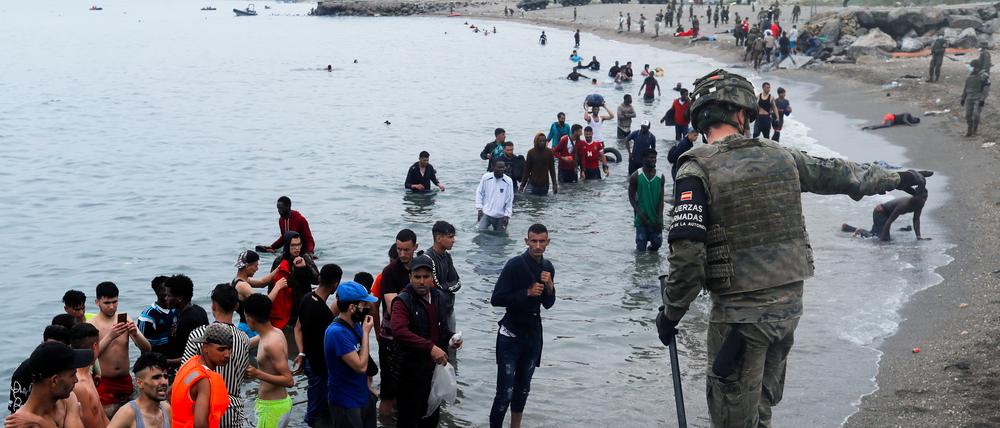 Ein spanischer Soldat weist marokkanische Migranten zurück, die im Meer vor der Exklave Ceuta versucht haben, Spanien zu erreichen.