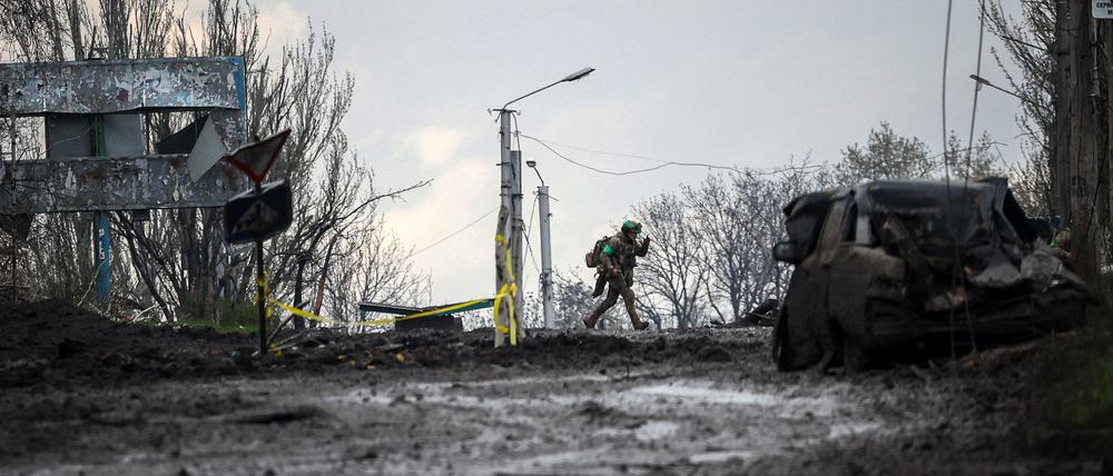 Ein ukrainischer Soldat läuft vor dem Beschuss über eine Straße in der Frontstadt Bakhmut in Deckung