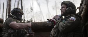Ein ukrainischer Soldat der Asow-Brigade, bekannt unter dem Rufnamen Chaos, rechts, trägt eine Mörsergranate, während er auf einen Feuerbefehl wartet. 