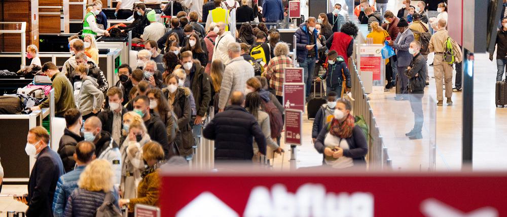 Zahlreiche Fluggäste warten im Terminal 1 des Flughafens BER in einer Schlange auf die Sicherheitskontrolle.