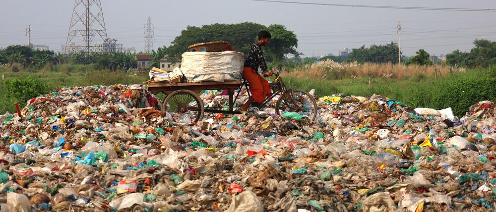 Bangladesch, Dhaka: Das niedrige Land auf beiden Seiten einer Straße wird mit Müll aufgefüllt. Diese Flächen sollen später für Wohnbauprojekte genutzt werden.