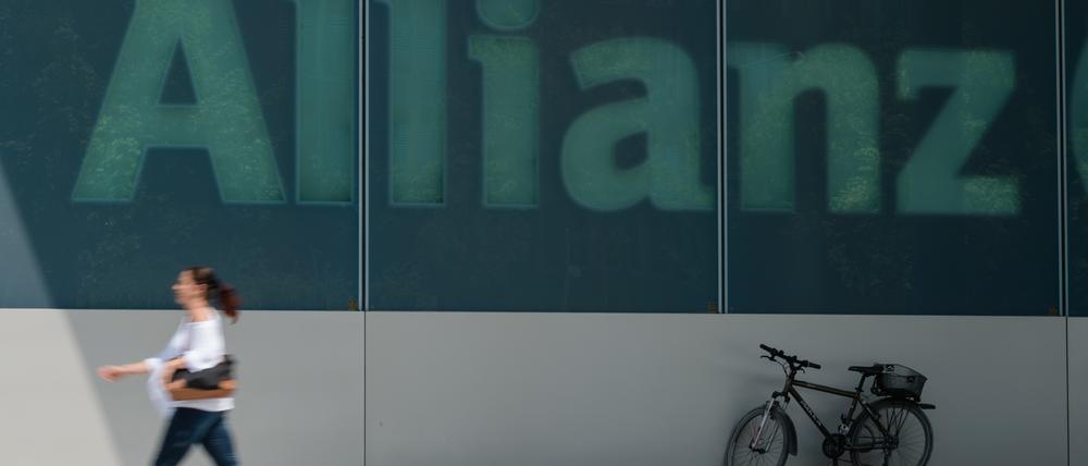 Eine Frau geht am an dem Schriftzug „Allianz“ an einem Gebäude des Versicherungskonzerns vorbei. 