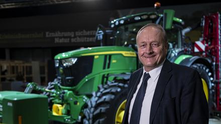 Joachim Rukwied, Präsident des Deutschen Bauernverbandes steht vor der Eröffnung der Grünen Woche auf dem Erlebnis-Bauernhof vor einem Traktor.
