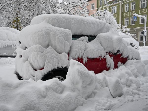 Eine dicke Schneeschicht liegt auf parkenden Autos in München.