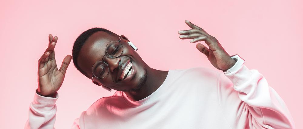 Young handsome african american man dancing, singing his favorite song with closed eyes, isolated on pink background
Ear-in-headphones