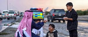 Ein Mann und Kinder werfen eine Handvoll Hagelkörner, die sie nach einem Unwetter im Bezirk Umm al-Haiman, etwa 55 Kilometer südlich von Kuwait-Stadt, aufgesammelt haben.