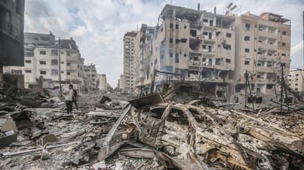 Palästinenser stehen inmitten zerstörter Gebäude in Gaza-Stadt.