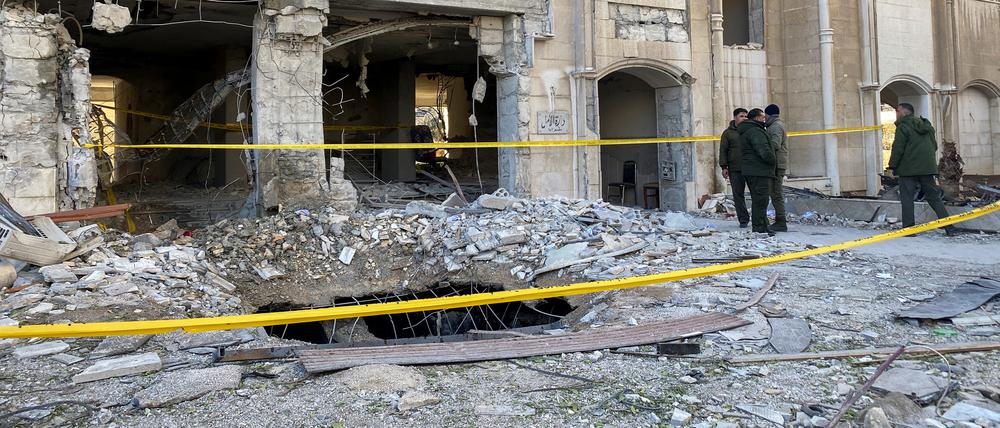 Polizisten stehen in der Nähe eines beschädigten Gebäudes am Ort eines Raketenangriffs im Kafr Sousa-Viertel im Zentrum von Damaskus.