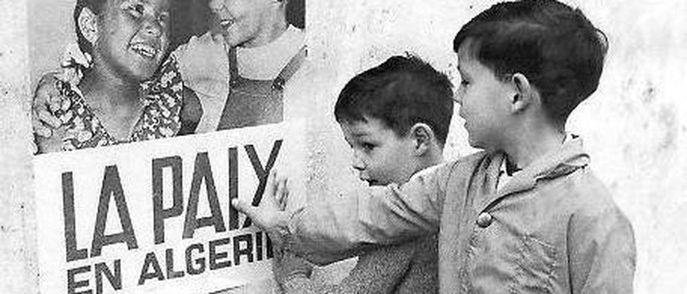 19. März 1962. Kinder in Algier vor einem Plakat der französischen Kolonialmacht, das den seit 16.06 Uhr geltenden Waffenstillstand verkündet. Foto: AFP