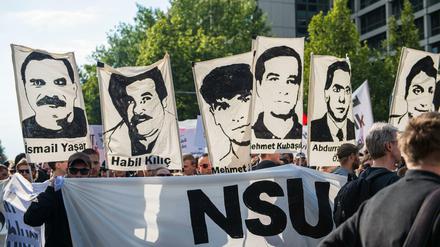 Demonstrierende halten bei einer Kundgebung Schilder mit Porträts der NSU-Opfer.