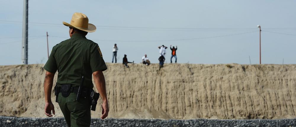 Grenzfälle: Hier, auf US-Seite, der Mann von der Border Patrol, dort, auf mexikanischer Seite, über dem Rio-Grande-Flussbett, die illegalen Grenzquerer, in der Nähe von McAlley, Texas