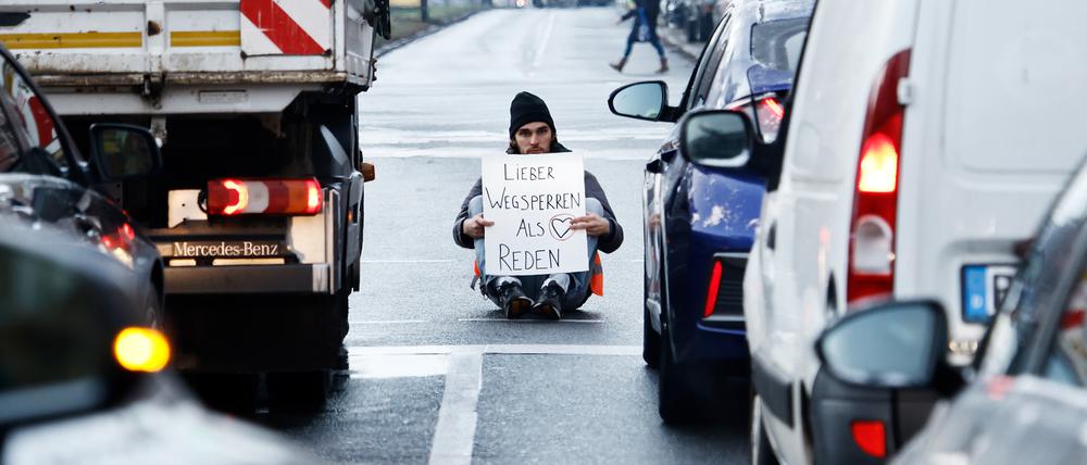 Ein Aktivist zeigt ein Schild mit der Aufschrift „Lieber Wegsperren als Reden“ bei einer Sitzblockade mit weiteren Aktivisten auf der Prenzlauer Allee. (Symbolbild)