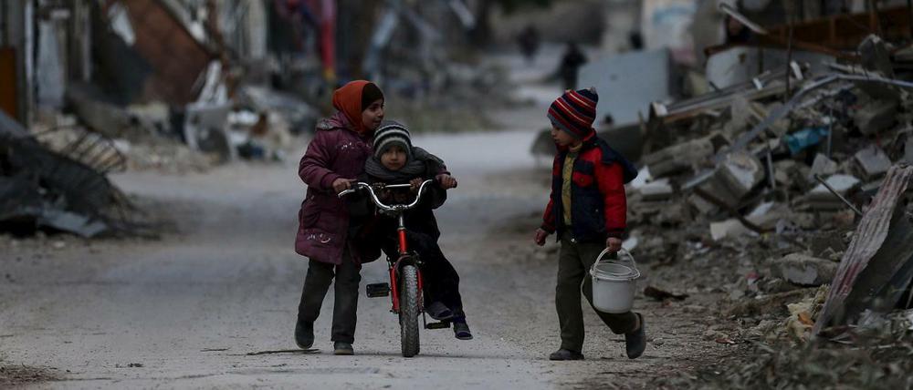 Drei syrische Kinder spielen in den vom Bürgerkrieg zerstörten Straßen von Joubar, einem Stadtteil von Damaskus.