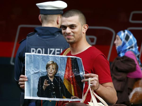 Ein Flüchtling hält am Bahnhof in München ein Bild von Angela Merkel hoch.
