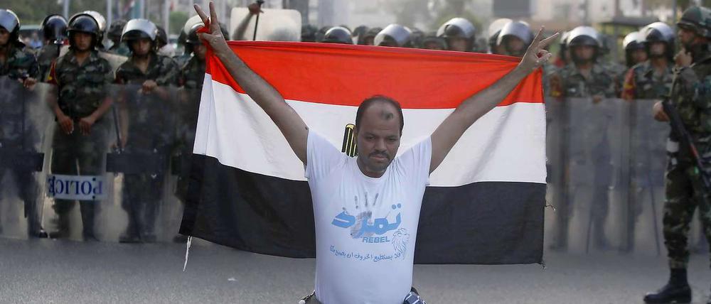 Ein Mitglied der "Tamarod-Rebellen" kniet am Mittwoch in Kairo mit der ägyptischen Flagge vor Armeesoldaten. Zehntausende Ägypter fordern Präsident Mursi seit Tagen auf, zurückzutreten. Am Mittwochabend wurde Mursi von der Armee entmachtet.