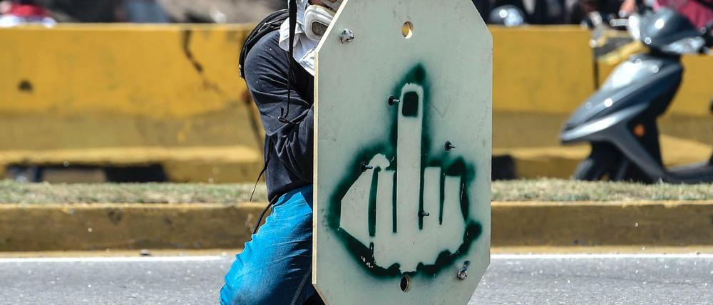 Ein Demonstrant in Caracas schützt sich hinter einem selbstgebauten Schild. 